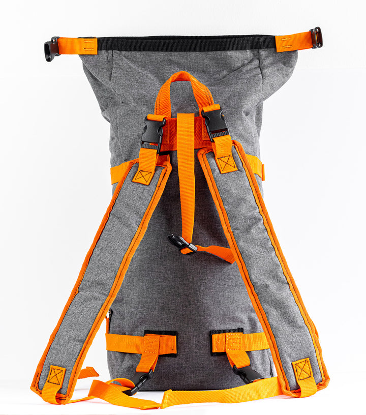 rear view of the backpack with the roll top full extended upwards.  This shows the opening from the rear, the sturdy stitching at the top and the buckles on the end.  the strap that holds the roll over top in place is seen fully extended in the rear picture.
