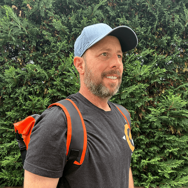 A person wearing the Grava Pannier Bag as a backpack, with the straps attached. The bag is securely worn on the person's back, offering convenience and versatility. The Grava logo and distinctive orange highlights are visible, adding a touch of style to the bag. This image showcases the multiple ways the Pannier Bag can be used, emphasizing its adaptability for different situations. Whether cycling or on foot, the bag transforms into a comfortable backpack, allowing for easy transportation of belongings.