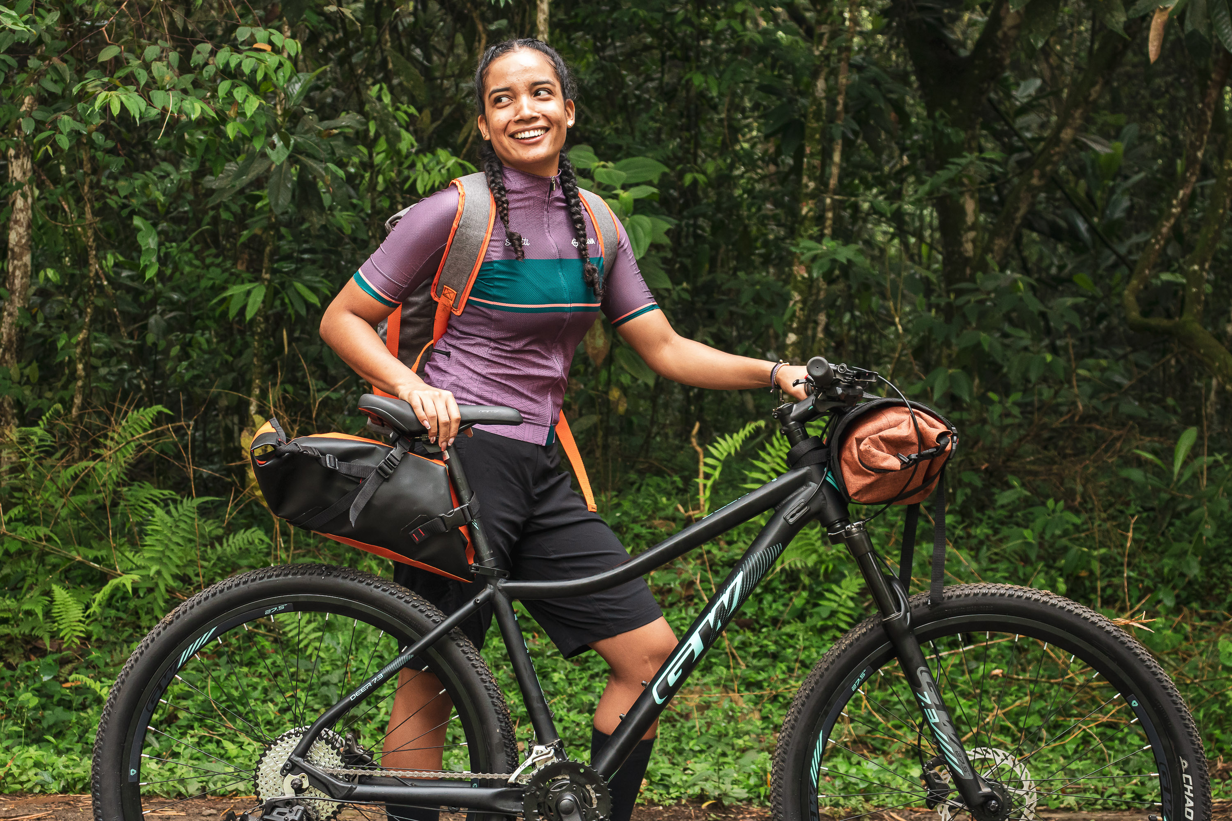A woman standing next to her bicycle in Grava gear and Bicycle Bags