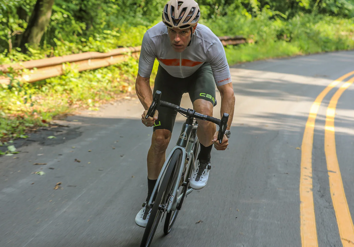 Cyclist riding on a road with greenery in the background