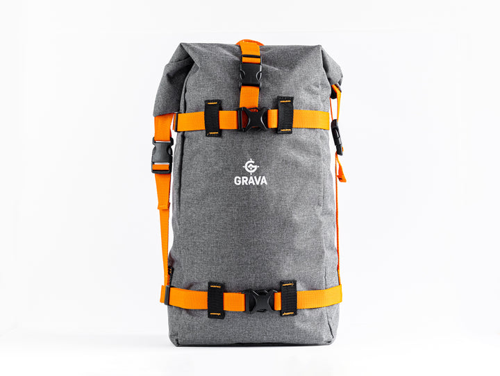 Front of Grava Cycling Backpack showing the Grava Logo.  You can see the durable grey canvas and the buckles for the two orange straps that wrap around the front.  It is a sleek and easy to use design.  