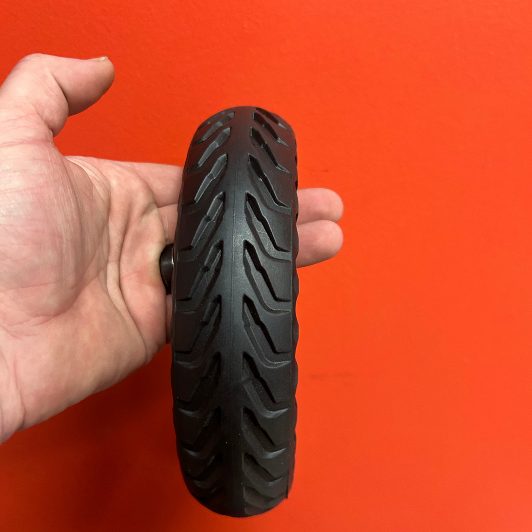 Hand holding a black tire against an orange background