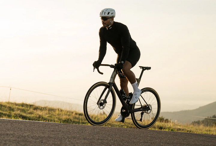 Person riding a bicycle on a road with a scenic background