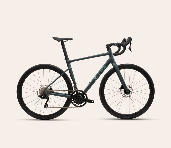 X-LAB RS5 Shimano 105 mechanical 12-speed road bike in Hydrostatic Blue, full bicycle drive-side view on a warm #F6EFE9 background