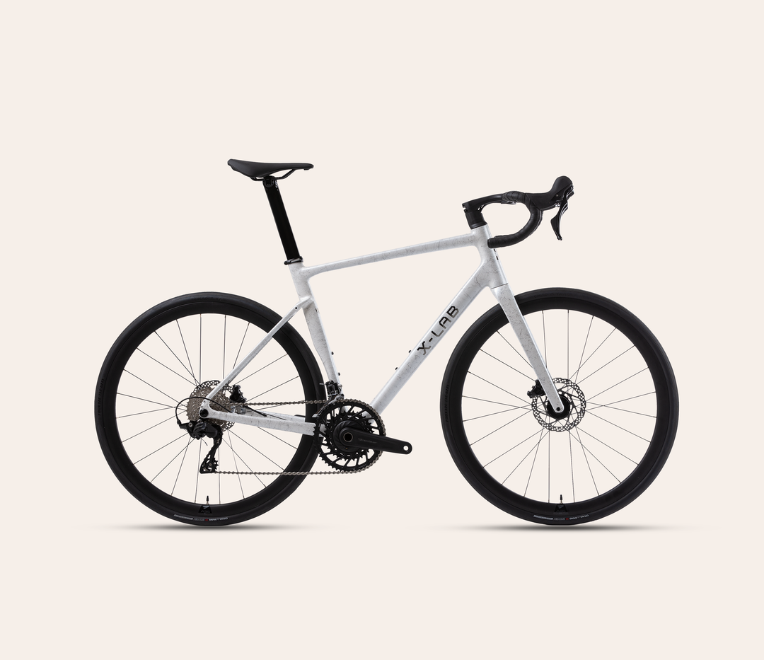 X-LAB RS5 Shimano 105 mechanical 12-speed road bike in Wavebreaker White, full bicycle drive-side view on a warm #F6EFE9 background