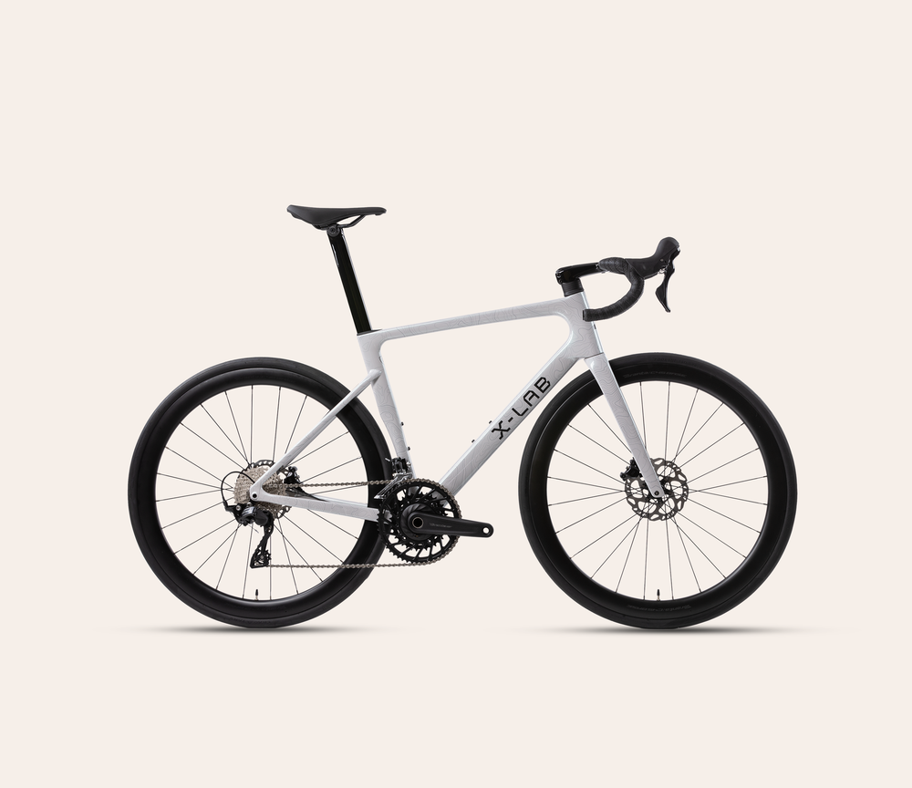 X-LAB RS7 Shimano 105 mechanical 12-speed road bike in Angel Wing White, full bicycle drive-side view on a warm #F6EFE9 background