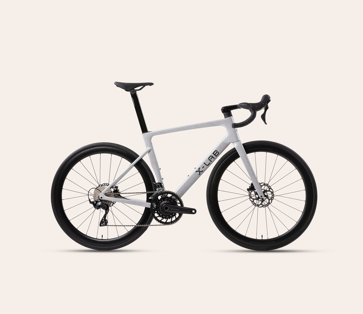 X-LAB RS7 Shimano 105 mechanical 12-speed road bike in Angel Wing White, full bicycle drive-side view on a warm #F6EFE9 background